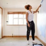 Woman-decorating-room-in-new-home-painting-wall.webp